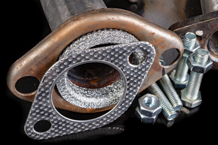 Car muffler, gaskets and bolts. Accessories and parts for car repair in the workshop. Dark background.