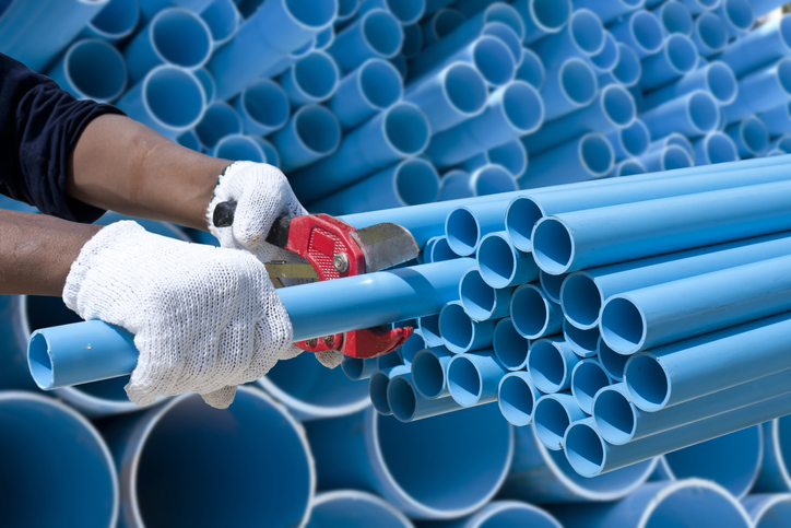 Worker cuting blue pvc pipe in construction site.