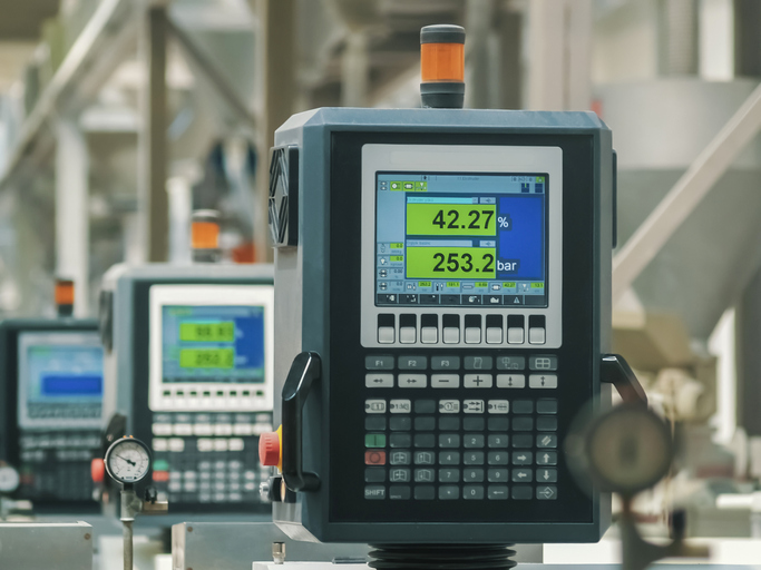 Heavy machines and digital displays in production line of a factory.